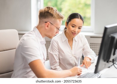 A Senior Specialist And A Junior Employee Are Sitting At The Table And Discussing Work Issues. A Man And A Woman Are Working In The Modern Office. Business, Teamwork And Problem Solving.