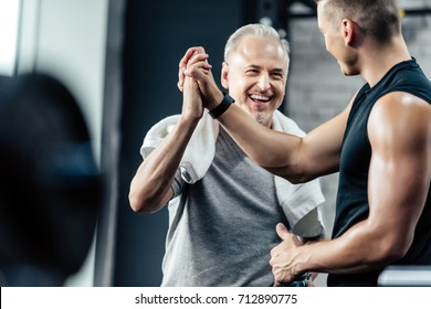 Senior Sportsman Giving Highfive To Trainer In Sport Center