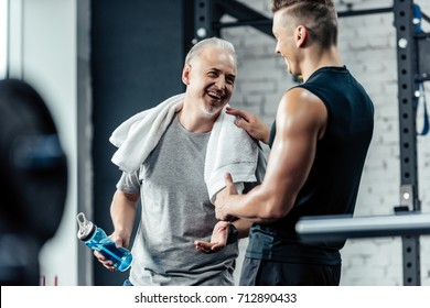 Senior Sportsman Shaking Hands With Trainer In Sport Center