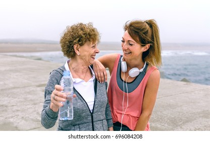 Senior Sportswoman Laughing With Female Friend By Sea Pier