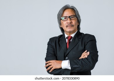 Senior staff with white hair wearing mustache glasses Standing with a fierce expression in a black suit a red tie holds the pen at the right hand. On white backdrop