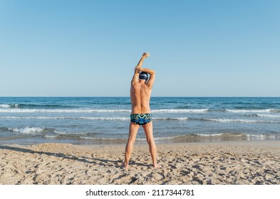 Senior swimmer stretching with his back to the camera before entering the sea. Training on the beach - Powered by Shutterstock