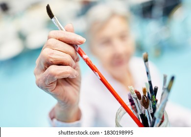 Senior takes a brush for painting in the painting therapy at the retirement home - Powered by Shutterstock