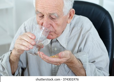 Senior Taking Medicine With Glass Of Water