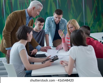 senior teacher with group of happy students in modern school classroom