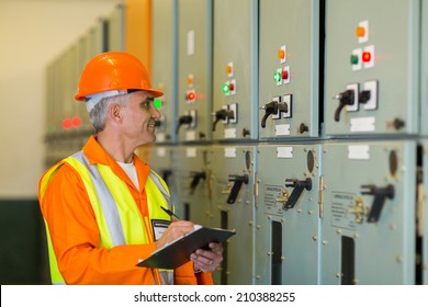 Senior Technician Writing Results Of Measurements In Power Plant Control Room