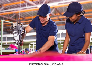 Senior Textile Worker Teaching New Employee About Cutting Material