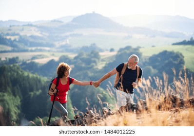 Senior tourist couple with backpacks hiking in nature, holding hands. - Powered by Shutterstock