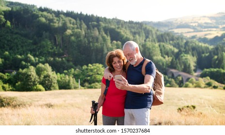Senior tourist couple hikers standing in nature, taking selfie.