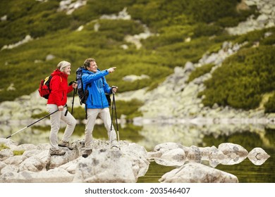 Senior tourist couple hiking at the beautiful mountains, tarn in the background - Powered by Shutterstock