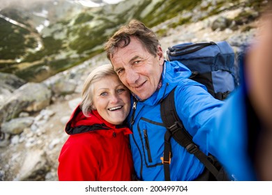 Senior tourist couple hiking and taking selfie at the beautiful mountains - Powered by Shutterstock