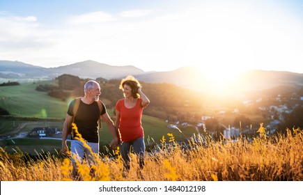 Senior tourist couple travellers hiking in nature at sunset, holding hands. - Powered by Shutterstock