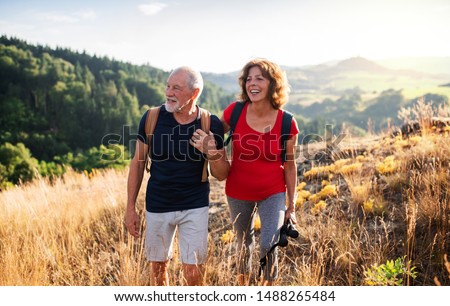 Senior tourist couple travellers hiking in nature, walking and talking.