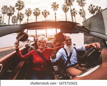 Senior trendy couple inside a convertible car on holiday time - Mature people having fun doing a road trip during summer vacation - Travel, fashion and joyful elderly concept - Main focus on man face - Powered by Shutterstock