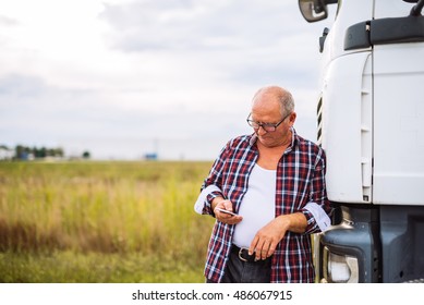 Senior Truck Driver Checking His Mobile Phone.