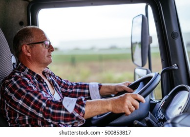 Senior Truck Driver Holding A Wheel And Driving.