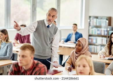 Senior University Professor Explaining Something To African American Muslim Student During A Class In The Classroom.