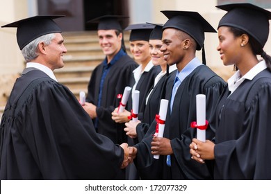 Senior University Professor Handshaking With Young Graduates