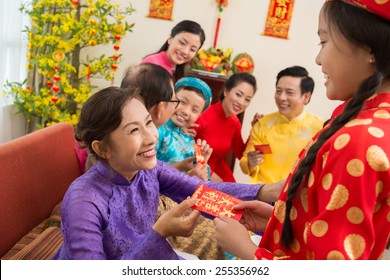 Senior Vietnamese Woman Giving Her Granddaughter A Red Envelope For Tet