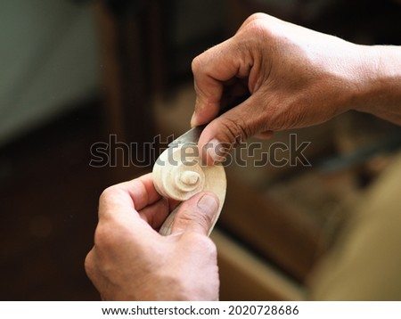 Senior violin maker carving and finishing a violin curl of an instrument model Stradivarius