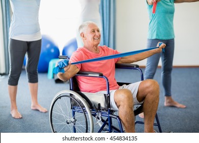 Senior In Wheelchair Exercising With Exercising Band During Sports Class