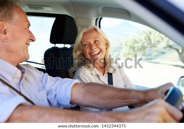 Senior white couple driving in their car,\
looking at each other, side view, close\
up