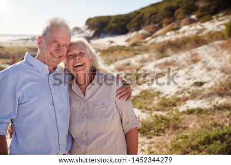Senior white couple standing on a beach embracing and smiling to camera, close up