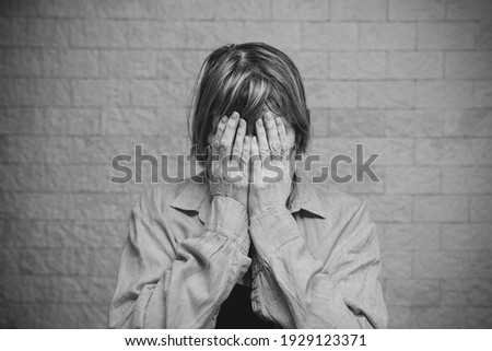 Senior woman addict and alcoholism alone depression stress sitting on the floor with her head in her hands. headache, dizziness, migraine. Social documentary concepts black and white
