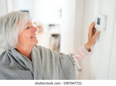 Eine Senior-Frau, die ihr Thermostat zu Hause einstellte