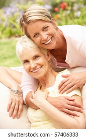 Senior Woman And Adult Daughter Relaxing In Garden