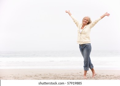 Senior Woman With Arms Outstretched On Winter Beach - Powered by Shutterstock