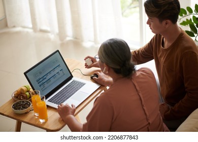 Senior Woman Asking Grandson To Help Her With Paying Bills Online