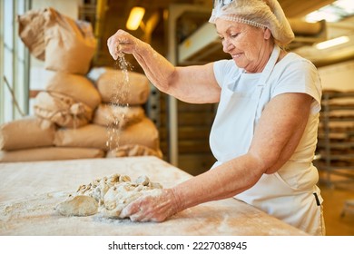 Senior woman baker with experience kneading dough with flour for baking in bakery - Powered by Shutterstock