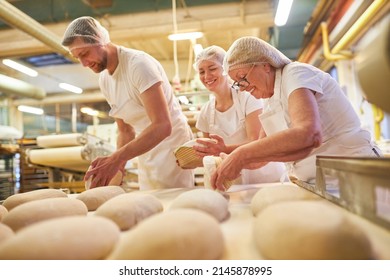 Senior woman as a baker with a team baking a loaf of bread in the family - Shutterstock ID 2145878995
