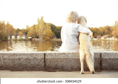 Senior Woman With Big Dog Sitting Back On Bund