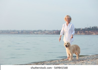 Senior Woman And Big Dog Walking On Riverside