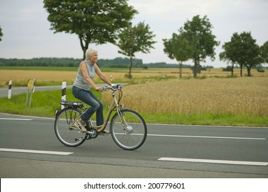 Senior Woman Biking On Road