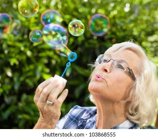 Senior Woman Is Blowing Bubbles In The Garden,close-up