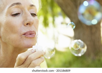 Senior Woman Blowing Bubbles Outdoors