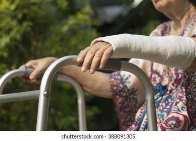 Senior Woman Broken Wrist Using Walker In Backyard.