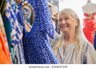 Senior Woman Buying Used Sustainable Clothes From Second Hand Charity Shop Or Thrift Store - Powered by Shutterstock