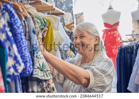 Senior Woman Buying Used Sustainable Clothes From Second Hand Charity Shop Or Thrift Store