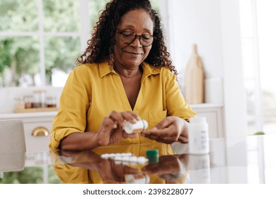 Senior woman carefully taking her prescription medication as part of her daily routine. Mature woman committing to her treatment plan as part of her chronic disease management at home. - Powered by Shutterstock