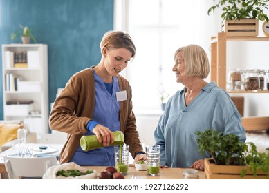 Senior woman with caregiver or healthcare worker indoors, drinking healthy smoothie.