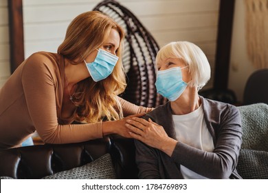 Senior Woman With Caring Daughter At Home. Females Wearing Medical Masks.