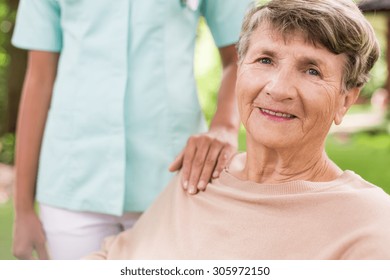 Senior Woman And Caring Nurse In The Garden