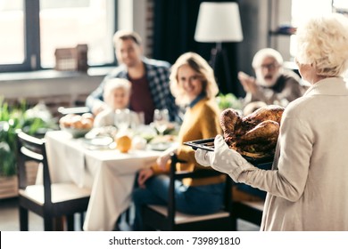 Senior Woman Carrying Thanksgiving Turkey For Holiday Dinner With Family