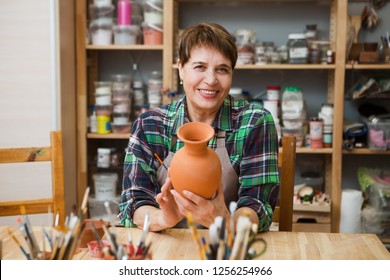 Senior woman in casual clothes and aprons at pottery workshop painting pottery. hobby on pension
 - Powered by Shutterstock