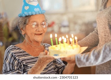 Senior woman celebrating birthday with cake, daughter surprise birthday cake for mother at home. - Powered by Shutterstock