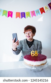 Senior Woman Celebrating Her Birthay At Home With Cake, Ballons And Confetti